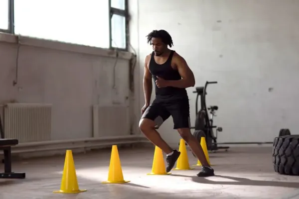 Photorealistic image of a volleyball player demonstrating agility, possibly using cones or a ladder drill, with a blurred Volley Pro in the background.
