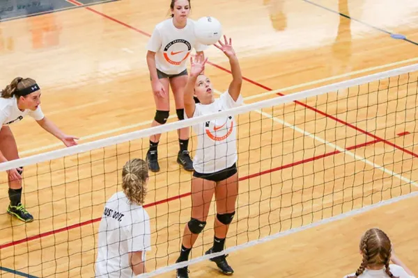 Photorealistic image of a volleyball setter delivering a perfect set to a hitter, showcasing precise hand positioning and technique.