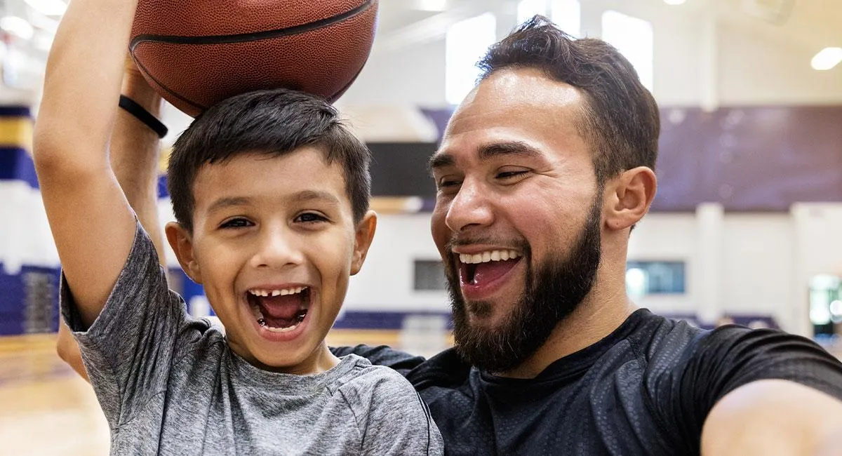 Smiling father and child enjoying a game of basketball and promoting a healthy lifestyle.
