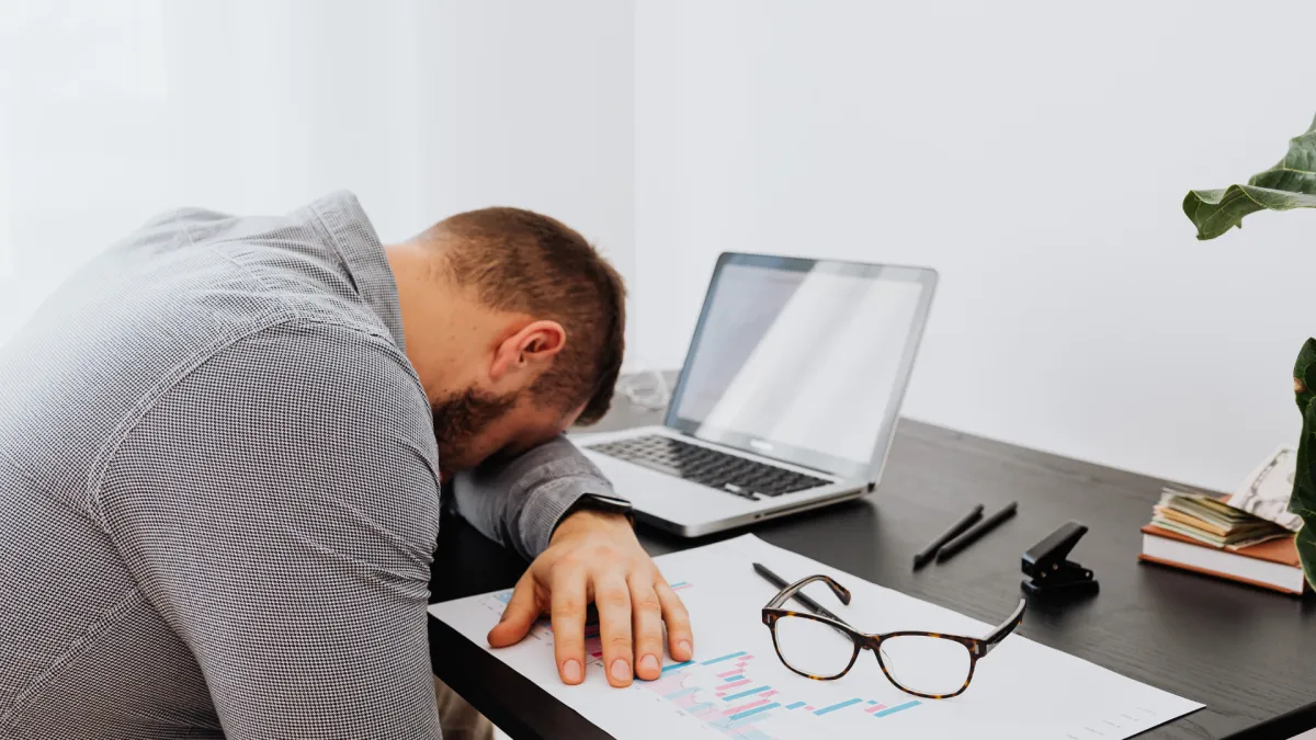 Fatigued man leaning over desk