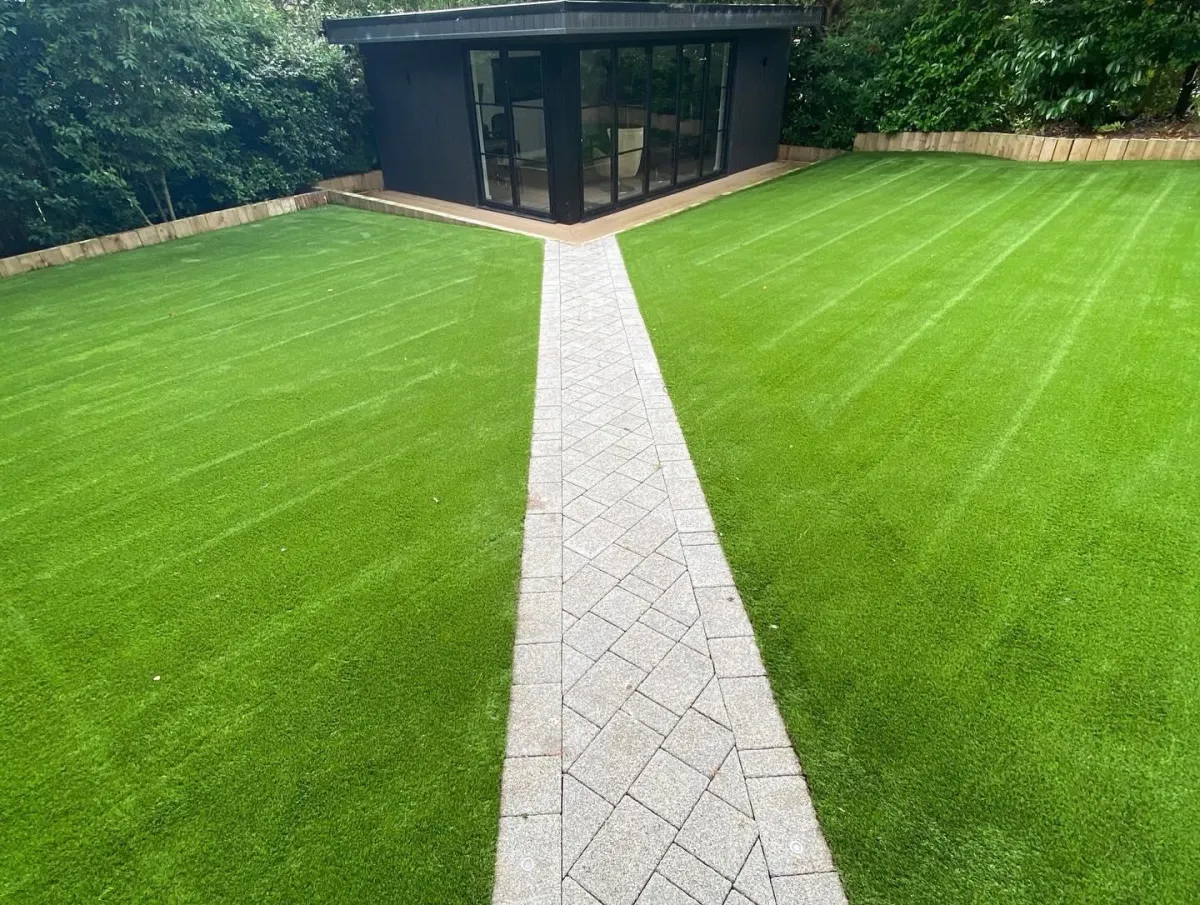 Artificial grass lawns with central paved path leading to a garden room