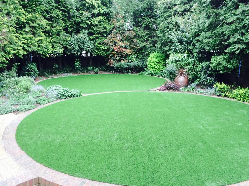 Curved artificial grass lawn with planted borders and mature trees