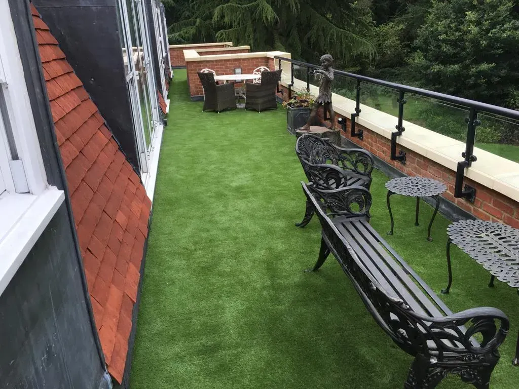 Roof terrace with artificial grass flooring, bench and outdoor tables