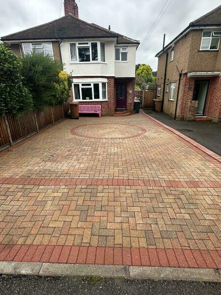 Clean block paving driveway with red brick border and circular feature outside a semi-detached house.