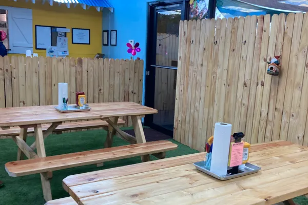 The interior of Dad's Grill, the newest family-friendly restaurant in Prescott Valley. The restaurant has the ambiance of a backyard get-together, with astro turf on the ground and several wooden benches. The walls look like a backyard fence, and there are gnomes and other yard decor in the restaurant.