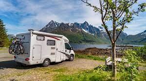 Motorhome parked in a scenic outdoor setting with mountains and trees in the background, showcasing the adventure and freedom of RV travel.