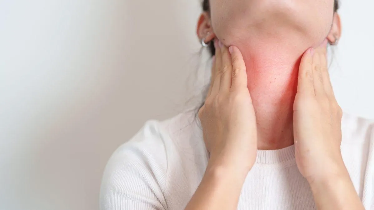 Image of woman holding her neck as her thyroid is inflamed