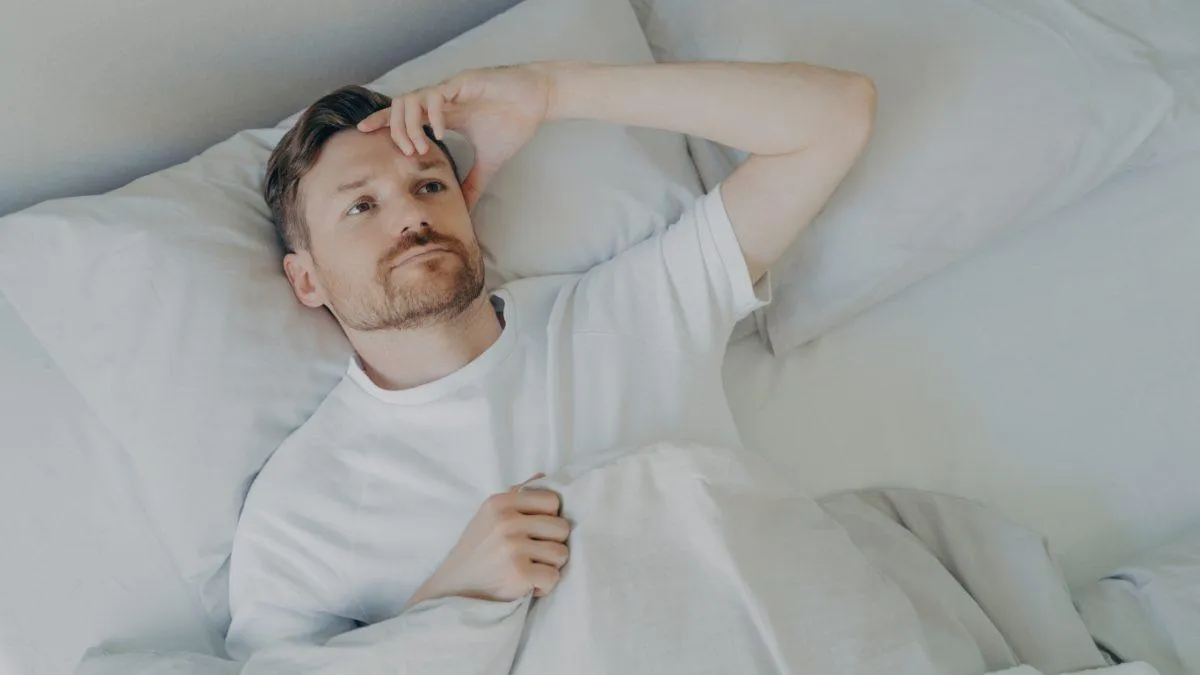 Man laying in bed, unable to sleep