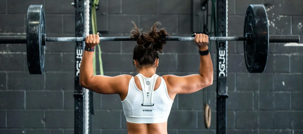 Strong woman lifting a heavy barbell in a gym, showcasing muscular strength and dedication to fitness training.