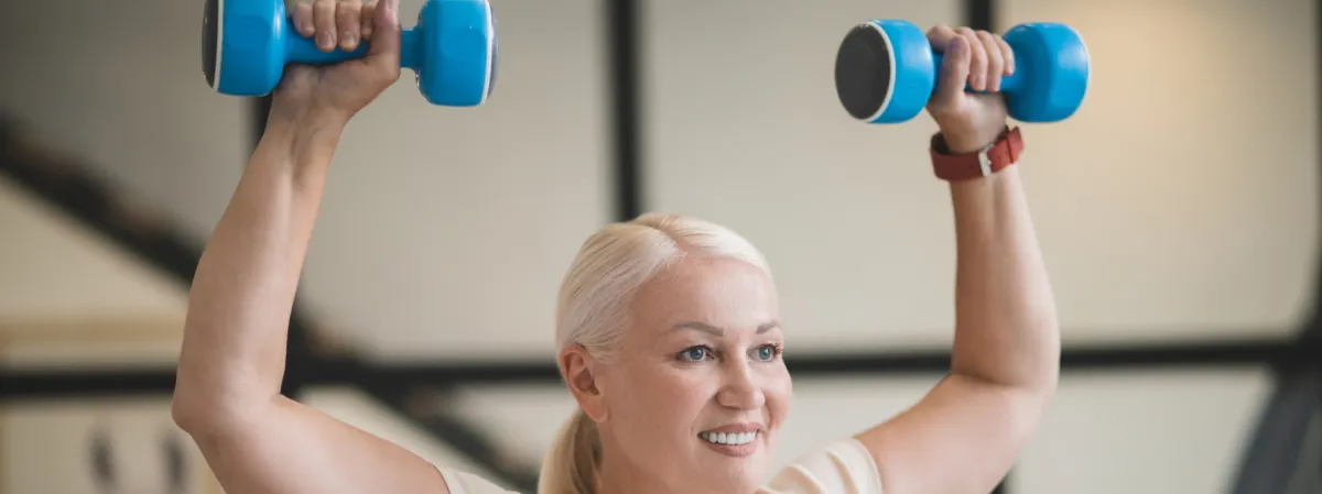 Woman performing overhead dumbbell press, showcasing strength training for women over 40