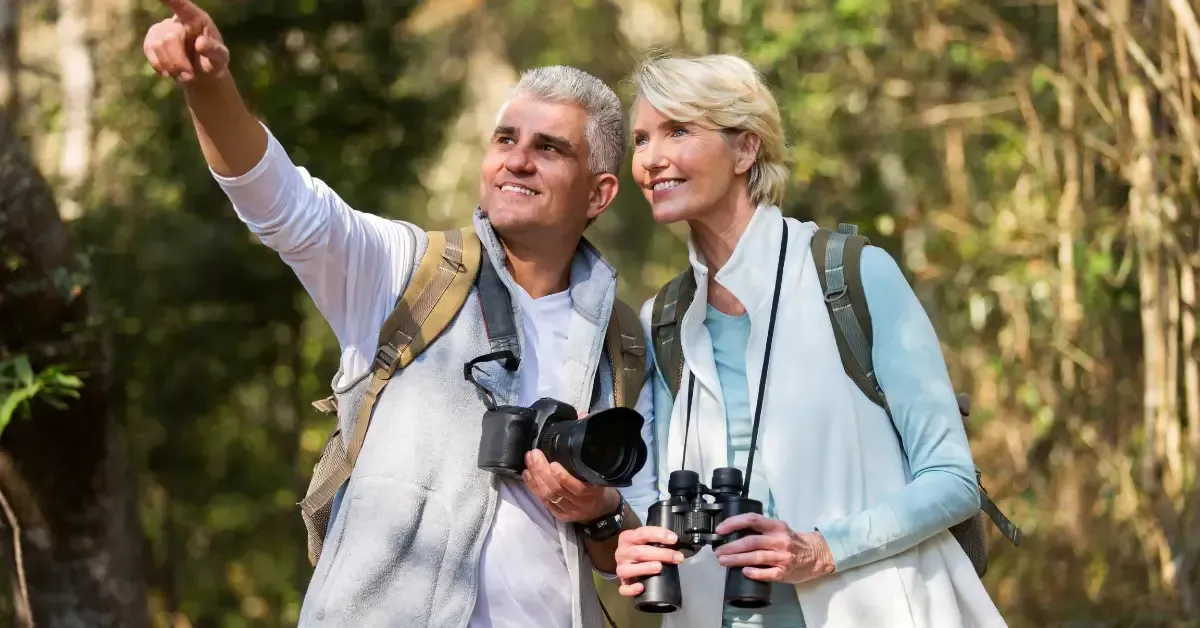 Active middle-aged couple birdwatching and hiking outdoors, representing how preventive hormone care and healthy lifestyle choices support vitality for adults over 40 in Hurricane, WV.
