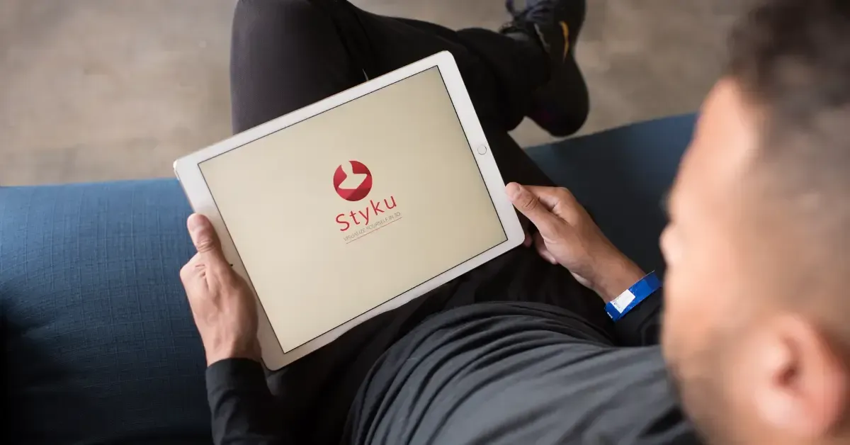 Man holding a tablet displaying the Styku 3D body scanning software logo.