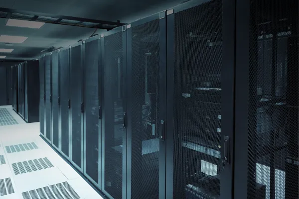 Row of secure server racks inside a modern AI data center, showing enclosed cabinets and raised floor infrastructure, representing large-scale compute facilities and hyperscale data center development.