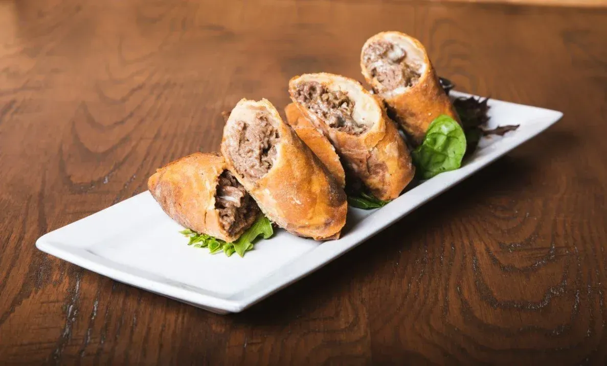 A plate with steak and cheese spring rolls
