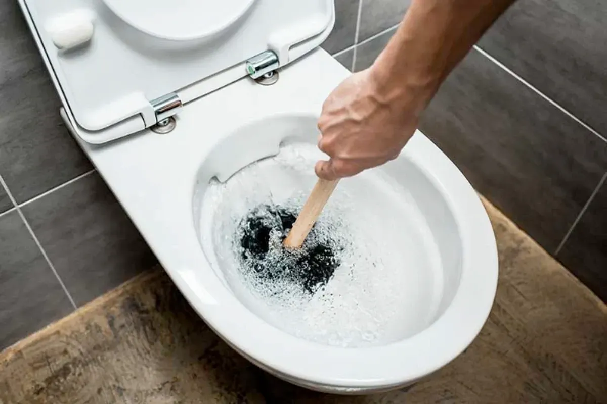 An overflowing toilet with someone plunging deep inside it