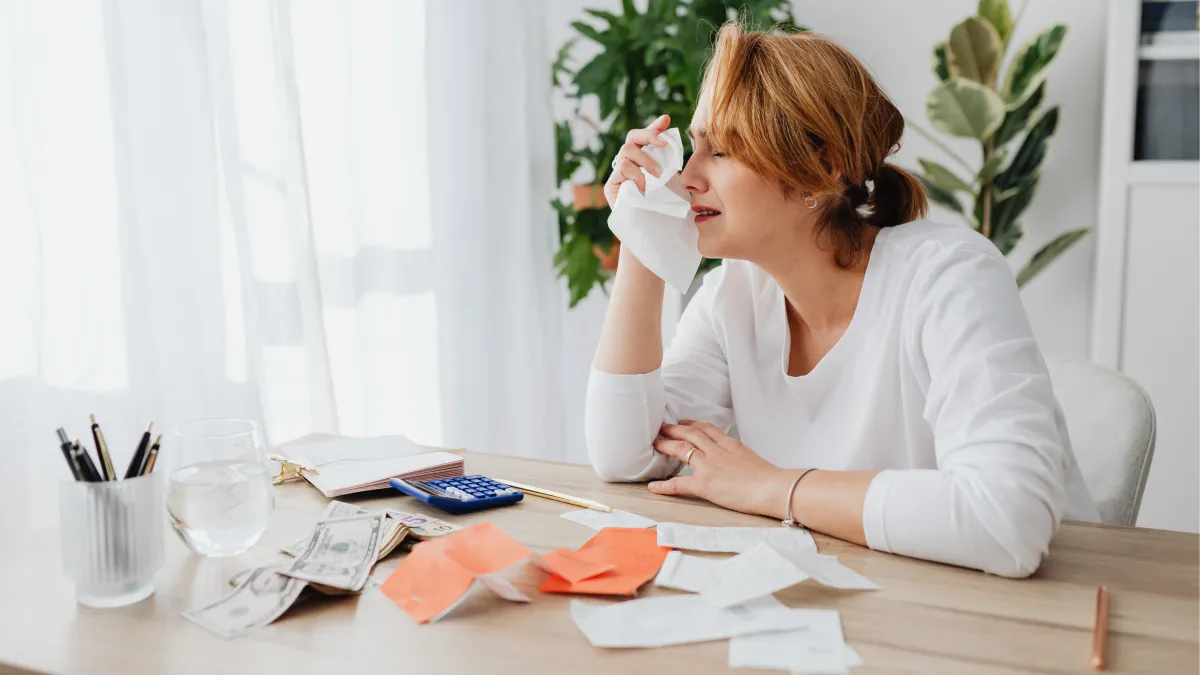 Stressed woman reviewing bills and receipts at home, symbolizing the emotional and spiritual weight of debt from a Christian perspective.