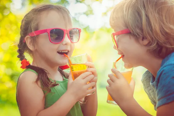Children drinking sugary juice boxes and sodas with smiles on their faces