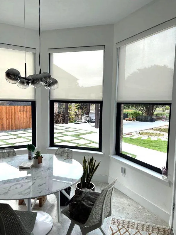  A simple white roller shade installed on a window above a kitchen sink.