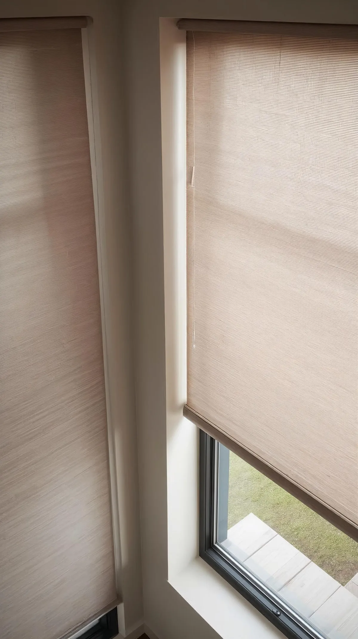 A person using a remote control to operate a motorized roller shade in a modern living space.