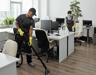 Professional cleaners sanitizing and tidying up an office space, ensuring a spotless and organized work environment.