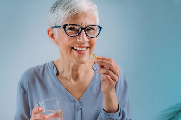 A woman taking an omega 3 supplement – building habits for long-term brain health