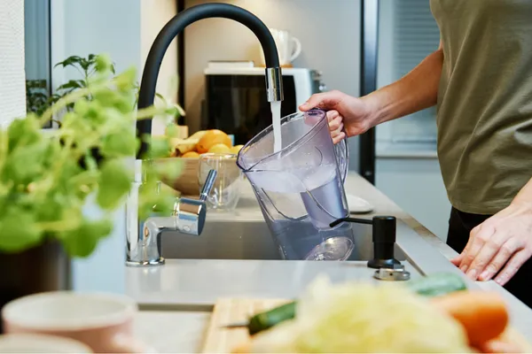 Man refilling a water filter jug to reduce lead exposure