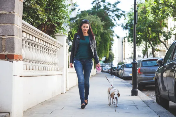 Woman walking dog outdoors in morning daylight for better sleep and brain health