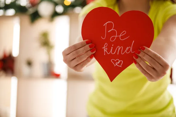 Person holding a red heart that says “Be kind,” representing kindness and emotional connection