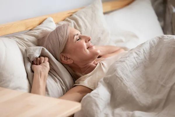 Perimenopausal woman waking refreshed after better sleep and reduced night waking