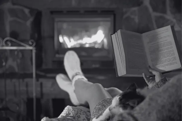 woman relaxing with fire, book and cat