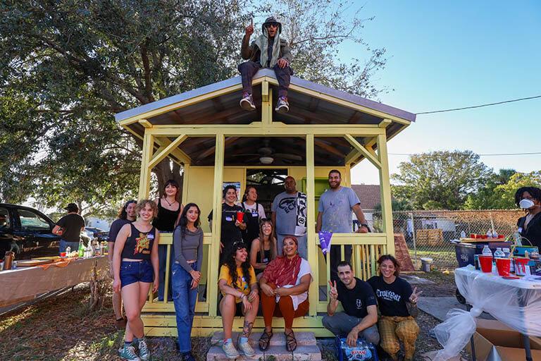 A group of organizers gathered around the newest Tampa Community Fridge, located inside a yellow shed outside Masjid Omar Al Mokhtar