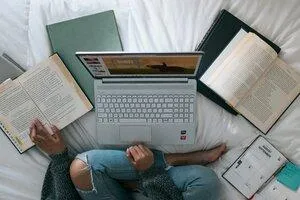 A woman surrounded by notebooks and laptop