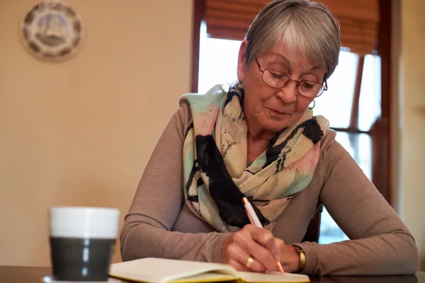 Image of a senior writing in a journal, creating a scrapbook, or sharing stories with loved ones.