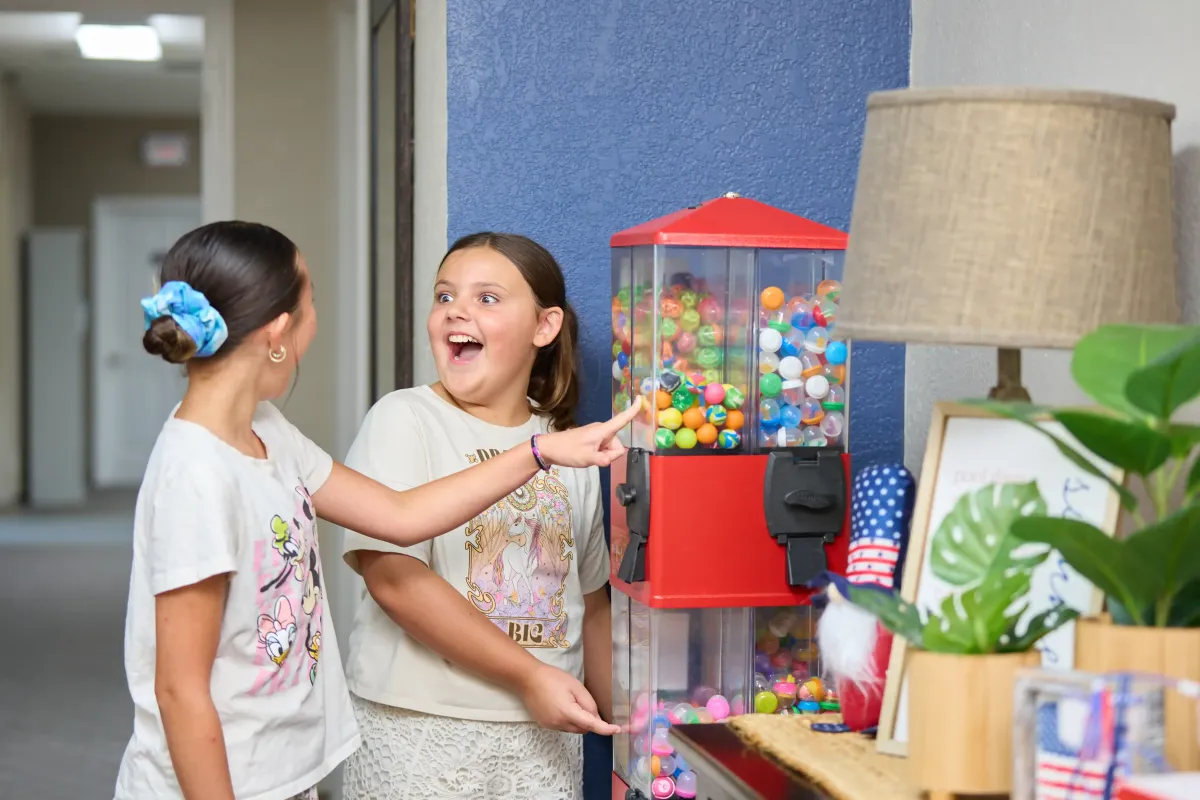 Two sisters smile with joy as they use the toy machines at Cardinal Dental of St. Peters