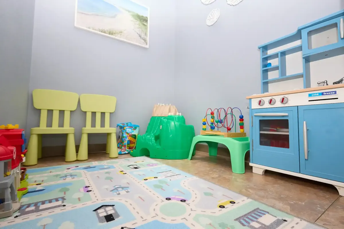 Bright yellow chairs and a play rug in the dedicated kids' section of the office