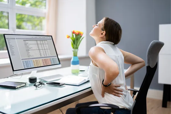 woman with back pain sitted at a desk