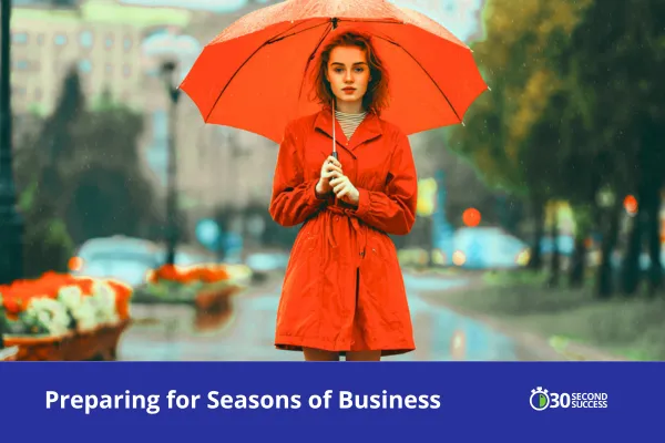 A woman wearing a bright red raincoat holds a red umbrella while standing on a rainy city street, symbolizing preparation and resilience during changing seasons in business. The image includes the title “Preparing for Seasons of Business” and the 30 Second Success logo at the bottom.