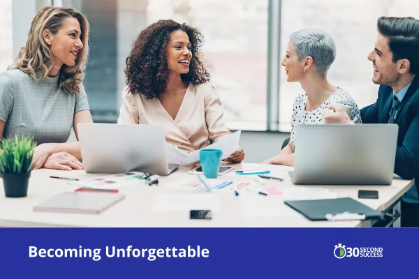 A diverse group of business professionals sit around a conference table smiling and engaged in conversation, each with a laptop open. They appear collaborative and connected in a bright, modern office. A blue banner at the bottom reads “Becoming Unforgettable” with the 30 Second Success logo.