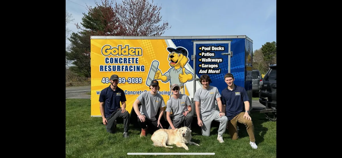 a team of people and a golden retriever sitting together in front of a Golden Concrete trailer