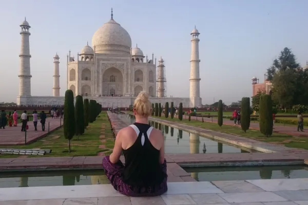 Emmely Christiansen sitting in front of the Taj Mahal, smiling softly—capturing a moment of peace and reflection during her travels through India.