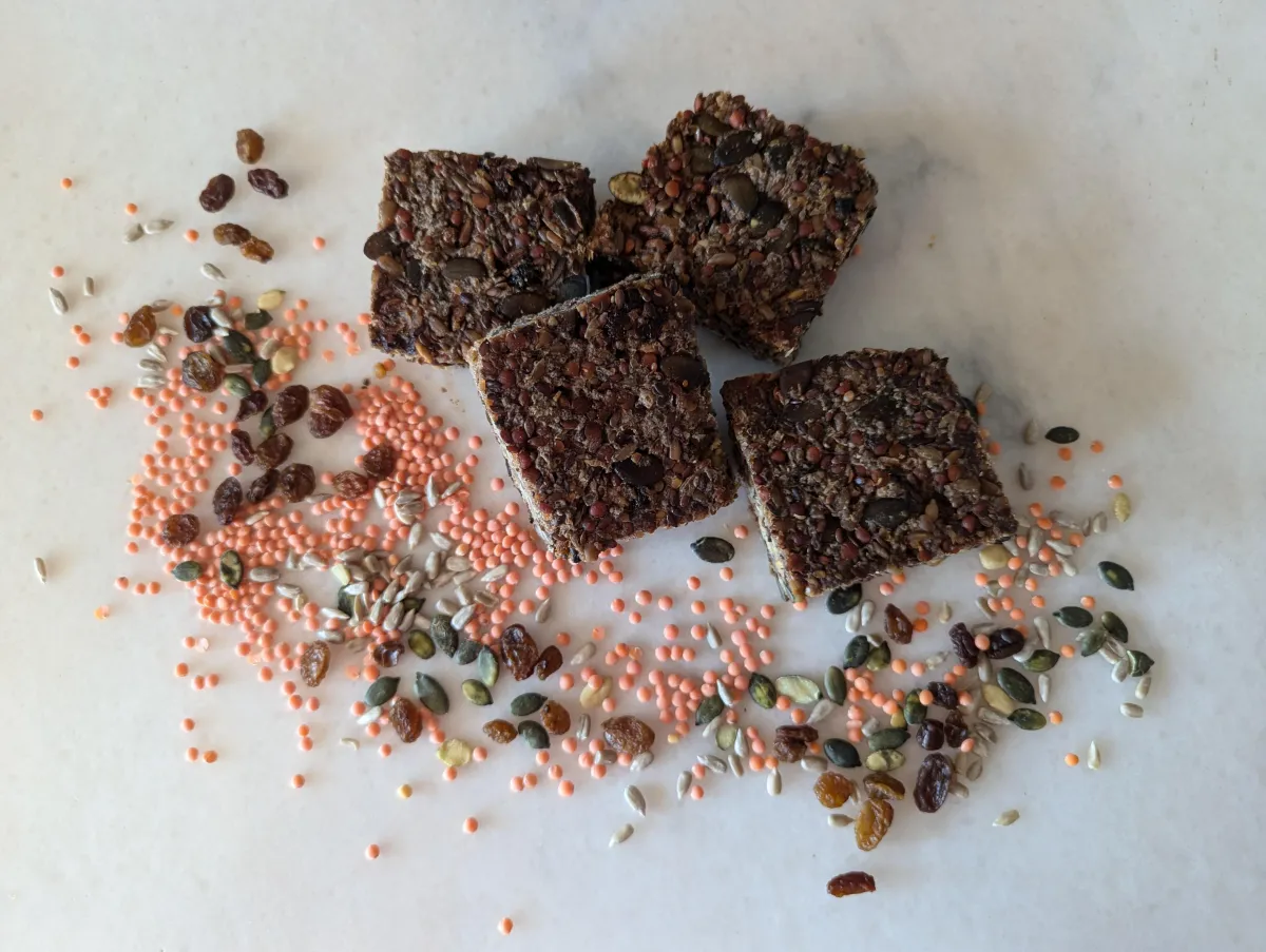 A sliced loaf of Emmely’s nutrient-dense seed and vegetable bread on a cutting board.