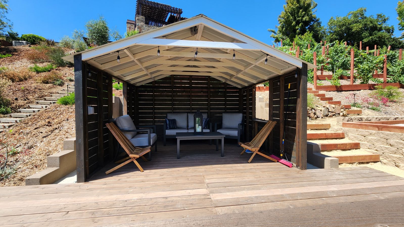 Modern wood pavilion with outdoor seating on a hillside terrace.