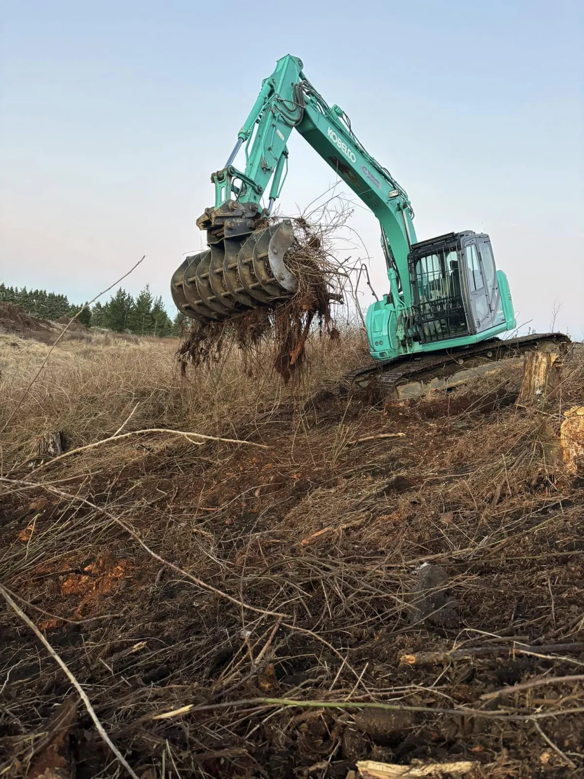 Excavator and construction workers preparing a gravel area for a building site.