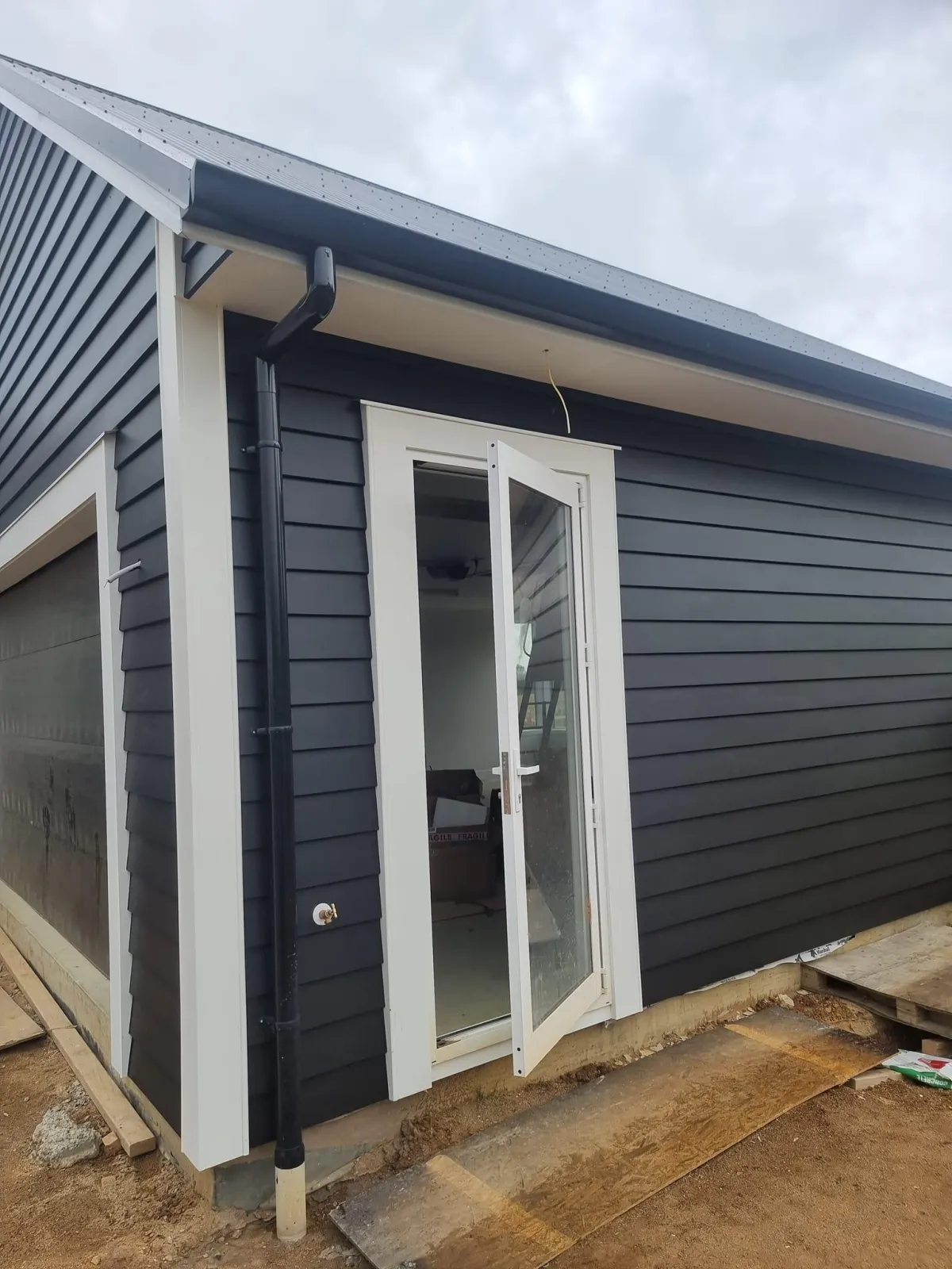 Dark weatherboard home with fresh coat and white doors painted by Elite Paint Co.