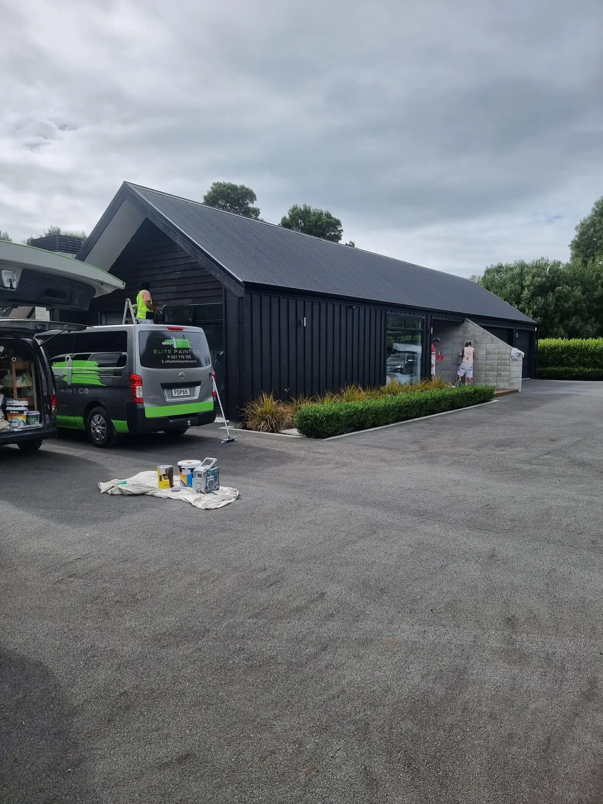 Elite Paint Co. van parked outside freshly painted black weatherboard home in Hamilton