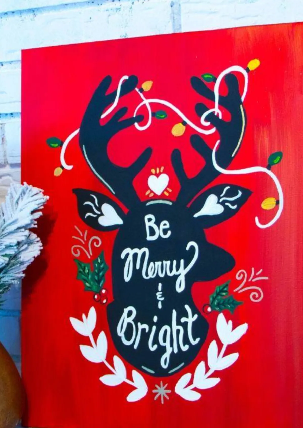 Red festive canvas painting with black reindeer silhouette, fairy lights and ‘Be Merry & Bright’ text – alternative office Christmas party idea Hull