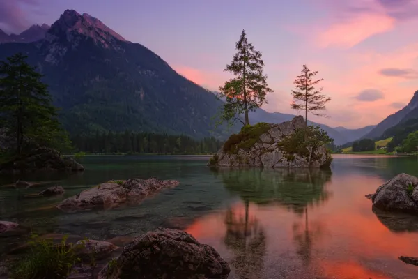 A mountain lake with a rock island where a tall tree stands beside a smaller tree, symbolizing the bond of motherhood and the guiding care of notaryhood.