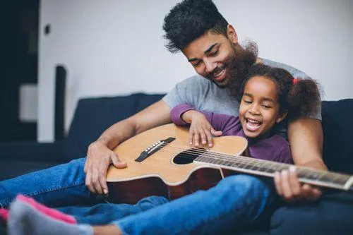 A father and daughter pose with a guitar