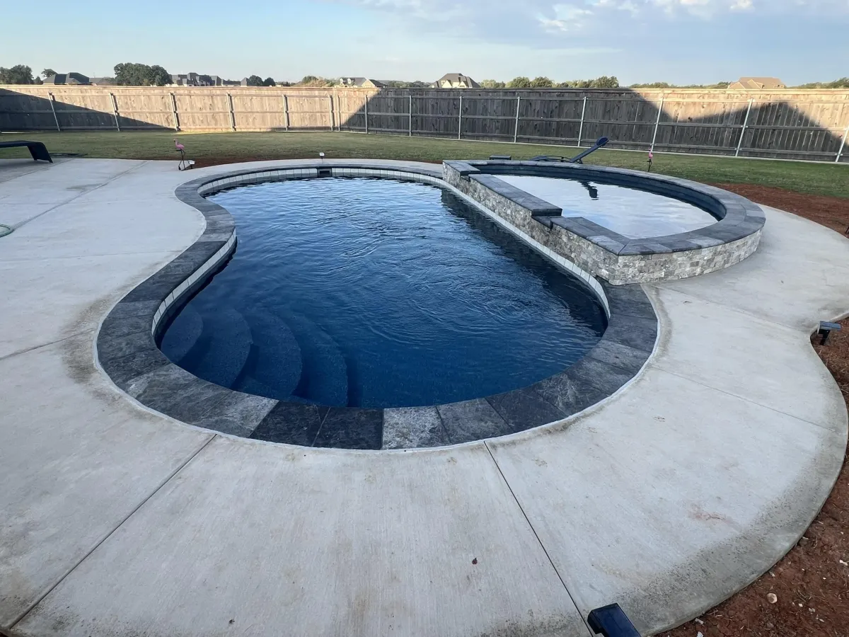 Backyard fiberglass pool with spillover tanning ledge