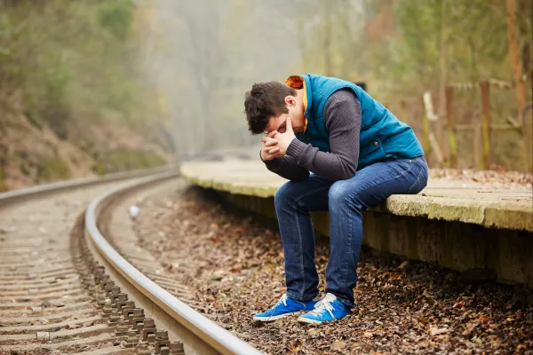 man on train tracks looking despondent